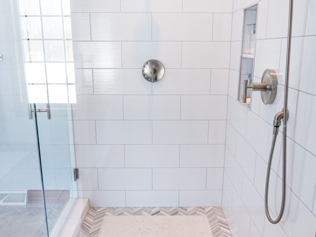 Inside of white tile shower with glass door