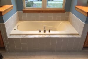 Gray tub surround with bathroom window above